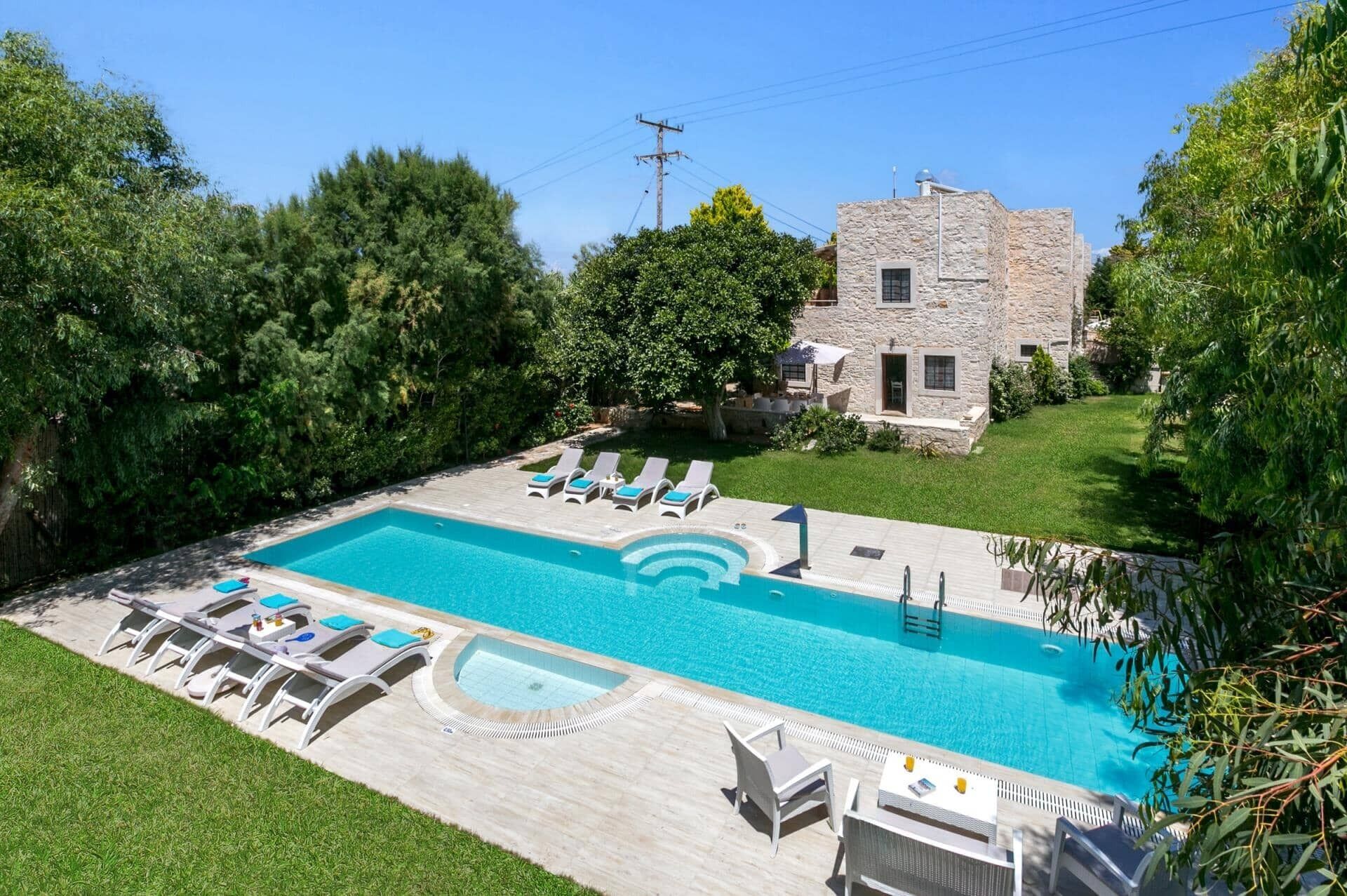 Una piscina rectangular con un edificio de piedra al fondo.