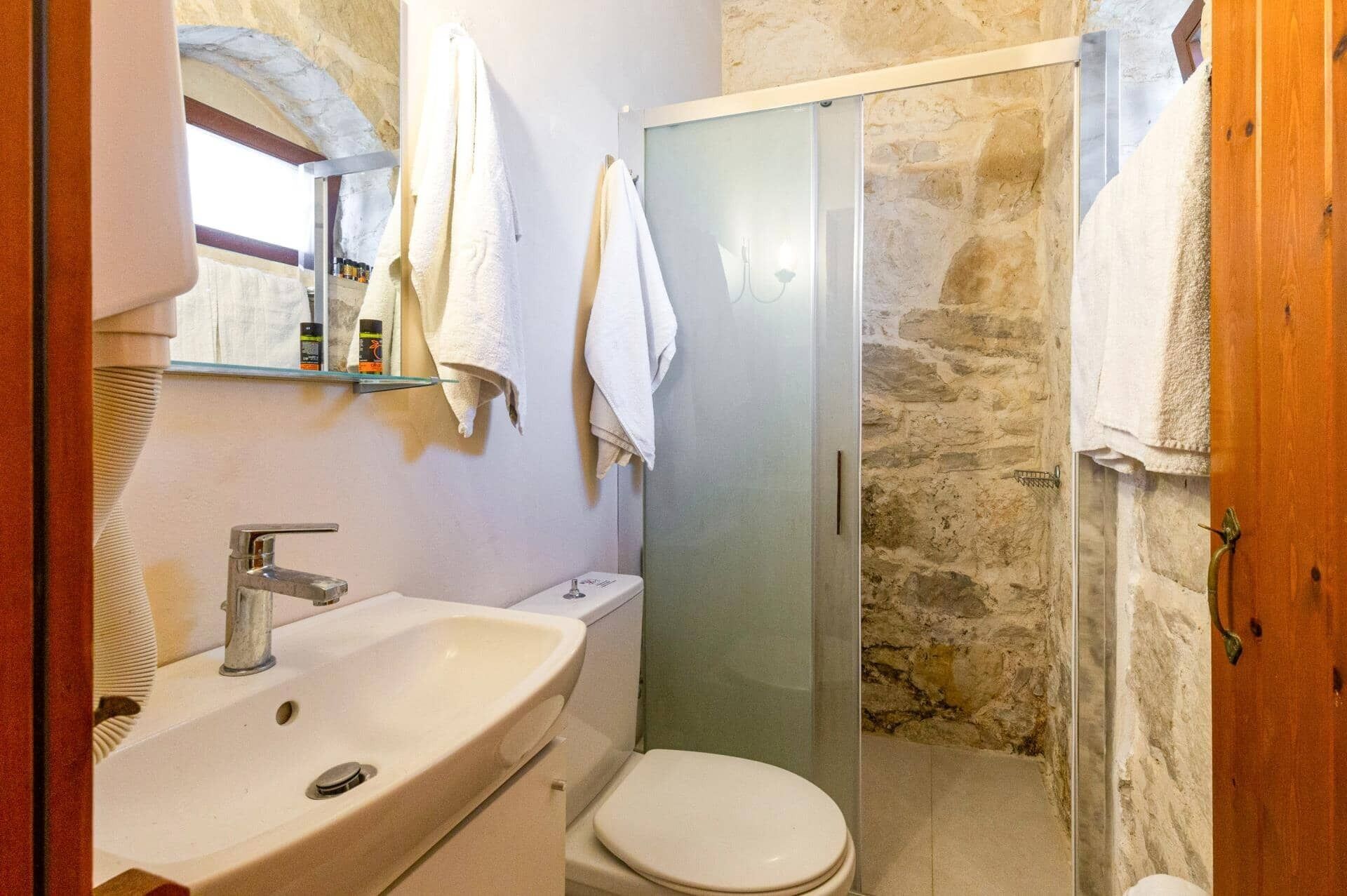 A bathroom with a sink, toilet, and a glass shower enclosure.