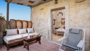 A stone-walled room with a bed, a wooden table with glasses, and a white chair. - Villa Vincenzos by Villa Plus (Agia Pelagia)