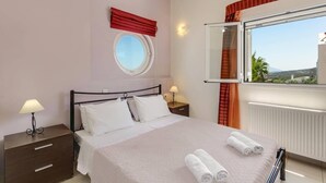 Una camera da letto con un letto, due comodini, una finestra con tende e uno specchio fissato al muro, con vista sull'esterno.