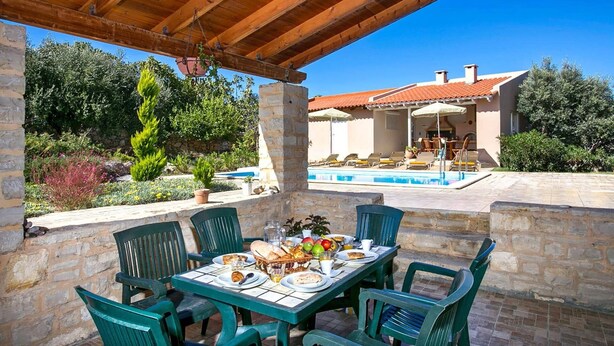 Area pranzo all'aperto con piscina e patio coperto.