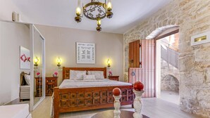 Ein Schlafzimmer mit einem hölzernen Bett, einer Steinwand, einem Holzschrank und einer Chandelier.
