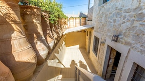 Eine schmale Steintreppe führt zu einem Gebäude mit einer Steinaußenwand und einem kleinen Fenster.