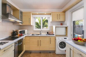 Une cuisine compacte équipée d’un four à micro-ondes, d’une cuisinière, d’un évier et d’un lave-linge encastré.