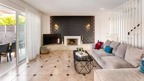 A living room with a fireplace, a sofa, a TV, and a dining area with chairs. - Villa Omega by Villa Plus (Chersonisos)