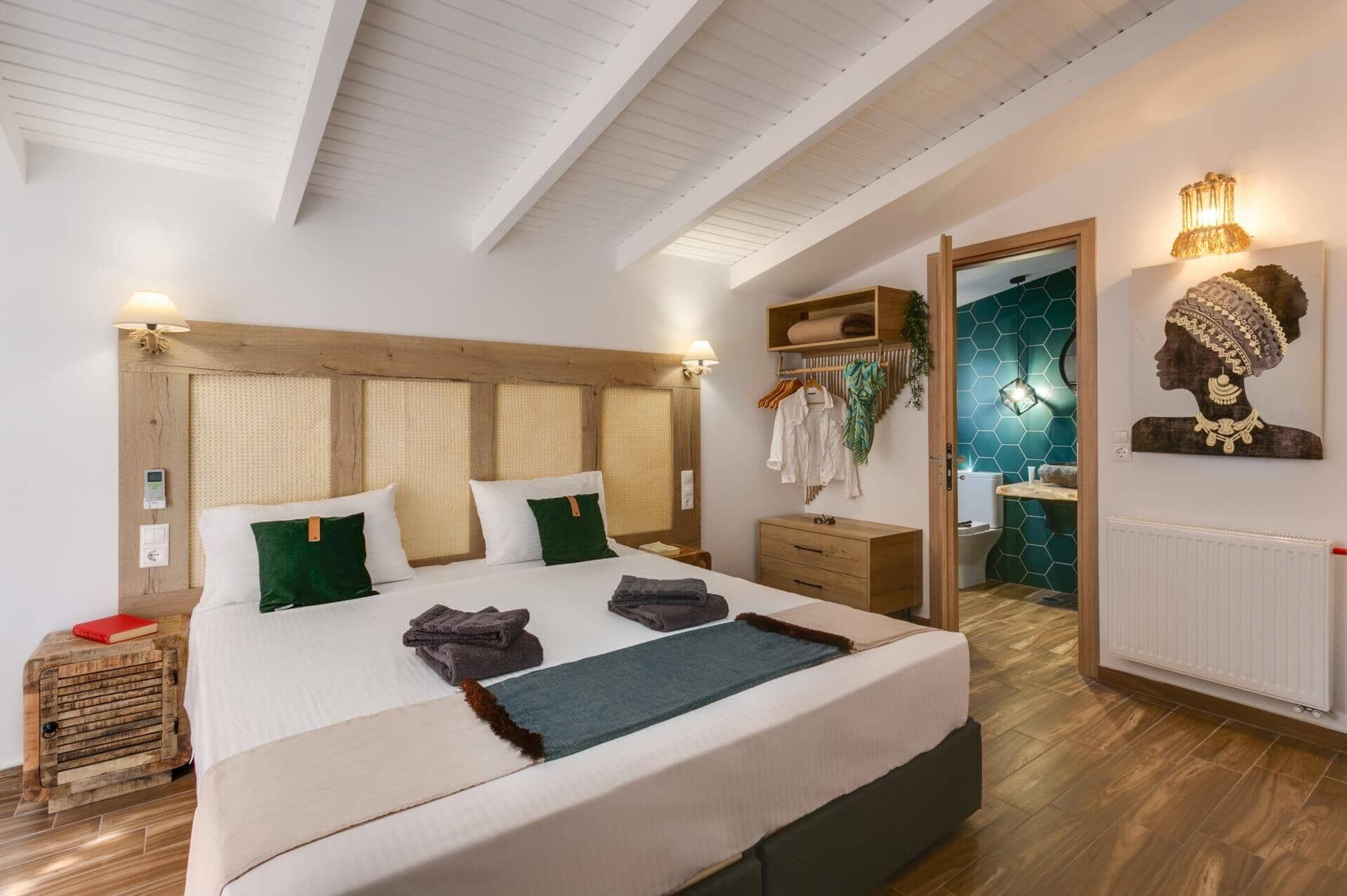 Een slaapkamer met een groot bed, een houten hoofdbord, nachtkastjes, een kledingkast en een badkamer die door een open deur zichtbaar is.