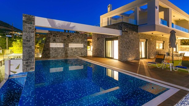 A modern house with a swimming pool, stone walls, and a clear view of the sky. - Villa Tropicana by Villa Plus (Hersonissos)