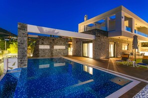 Et moderne hus med swimmingpool, stenvægge og krystalklar himmel.