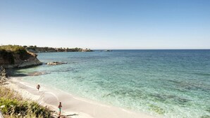 A beach with clear water, a sandy shore, and rocky outcrops. - Villa Tropicana by Villa Plus (Hersonissos)