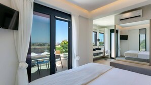 A modern hotel room with a large bed, a balcony with a view, a bathroom with a mirror and sink, and an air conditioning unit. - Villa Mariba White by Villa Plus (Malia)