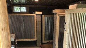 A room with a concrete floor, wooden walls, and metal-framed windows. There is a bench and a small table in the center. - Cabin 9 - Rustic Mountain Cabin Rental - Up to 3 persons (Hatfield)