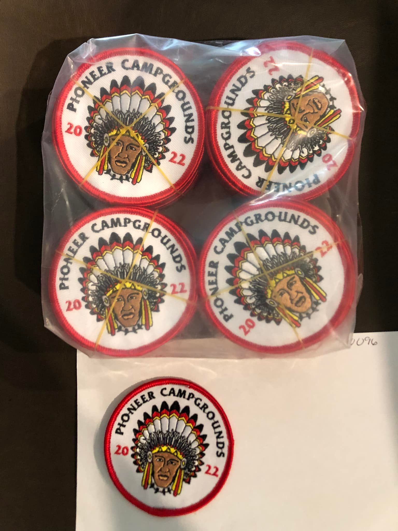Een plastic zak met vier Pioneer Campgrounds patches en één kleinere patch.