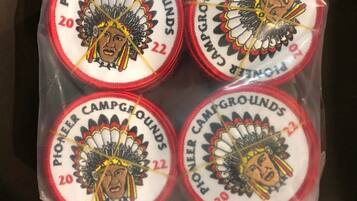 Een plastic zak met vier Pioneer Campgrounds patches en één kleinere patch.