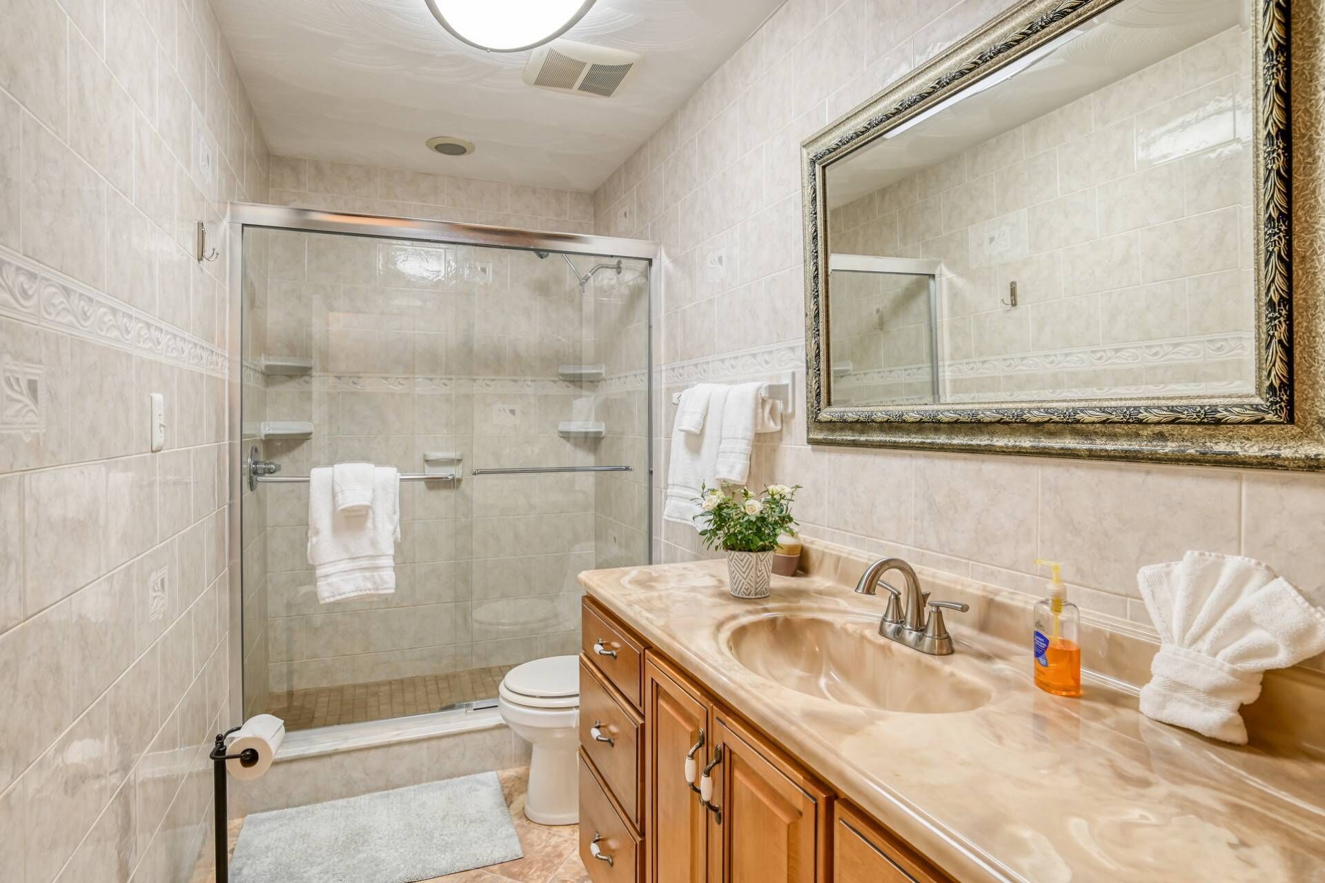 A bathroom with a glass-enclosed shower, a sink with a mirror, and a toilet.