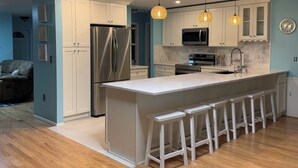 A modern kitchen with white cabinetry, stainless steel appliances, and a central island with bar stools. - 6min to Beach. Saltwater Pool,  Fits 8ppl. (Englewood)