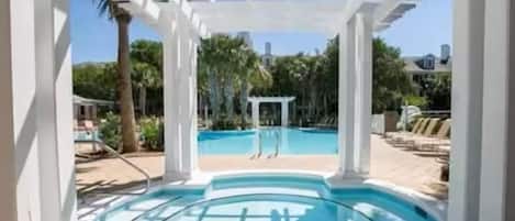 A pool area with a glass enclosure, white columns, and a view of a building in the background.
