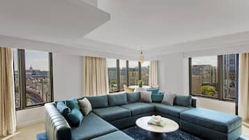 A modern living room with a sectional sofa, a round coffee table, and large windows offering city views.