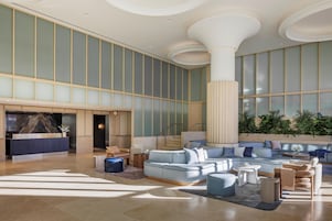 A spacious lobby with a reception desk, seating area, and large windows.