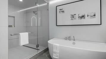 Une salle de bain moderne avec une douche à parois de verre, une baignoire sur pieds et une œuvre d’art encadrée au mur.