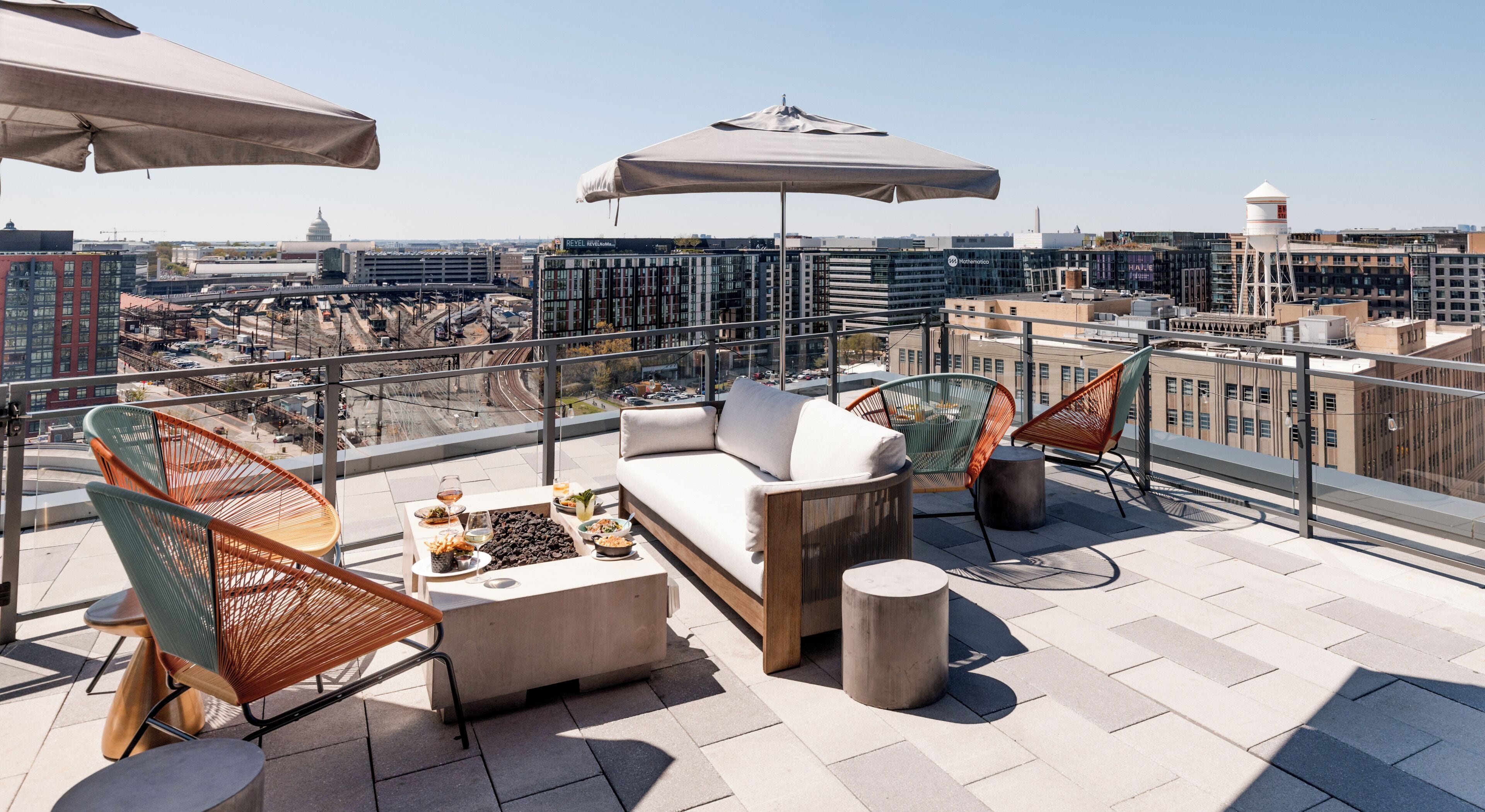 A rooftop terrace with outdoor seating, a table with drinks, and a city view.