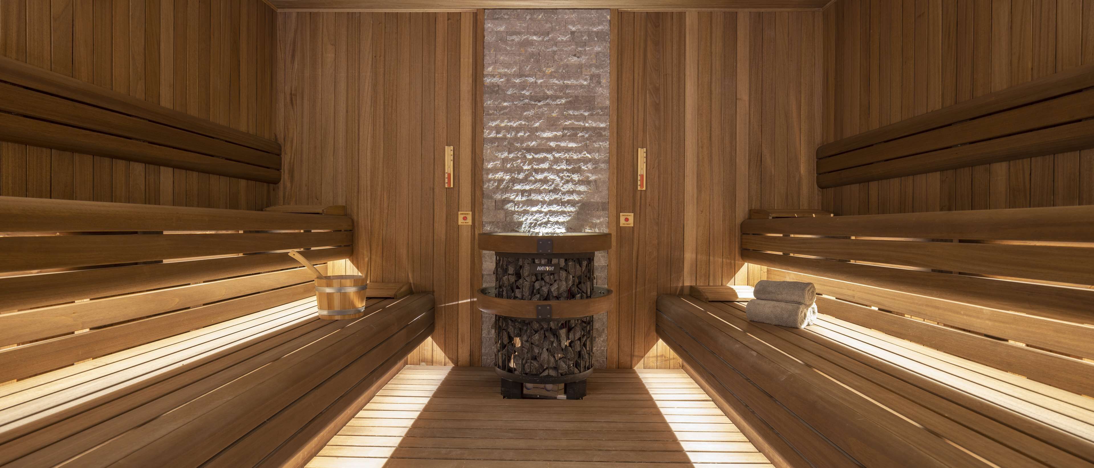 Una sauna con bancos de madera y una chimenea de piedra central.