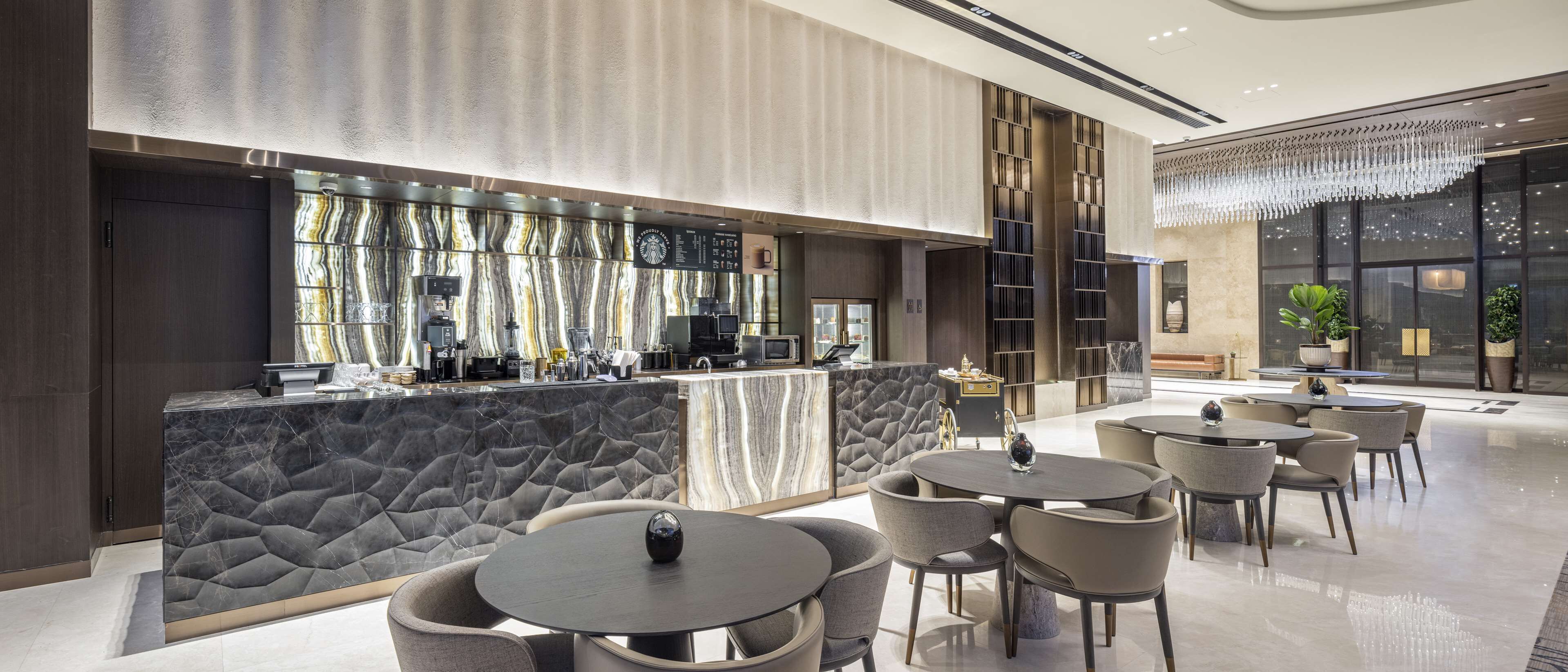 A modern bar area with marble countertops, a variety of bar equipment, and seating arrangements.