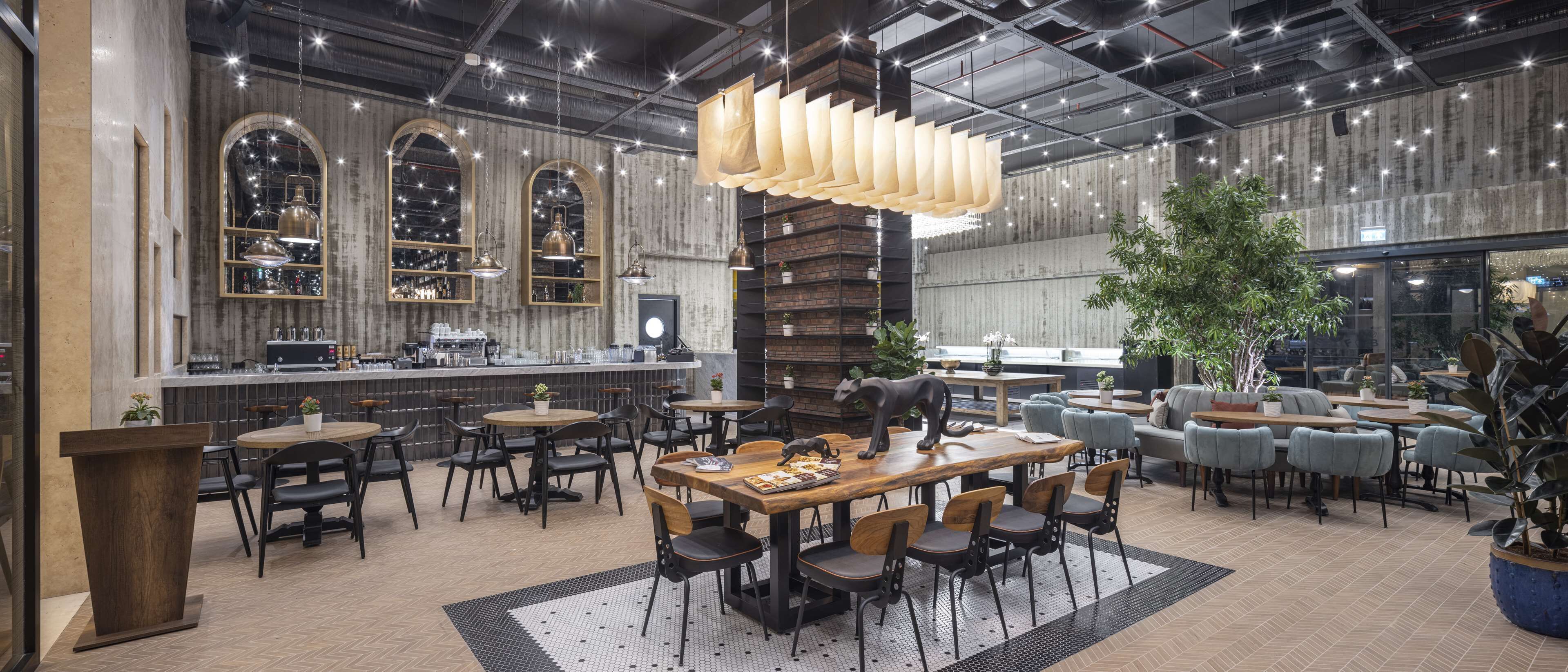 Un café moderno con una zona de bar, mesas y sillas de madera.