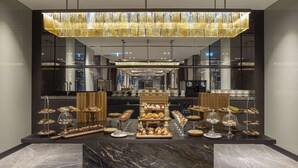 A modern hotel lobby with a marble reception desk, a large chandelier, and a buffet area with various food items. - Doubletree By Hilton Sanliurfa (Sanliurfa)
