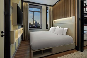 A modern hotel room with a large bed, built-in TV, and a city view. - Motto by Hilton Rotterdam City Centre (Rotterdam)