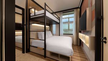 Una habitación de hotel moderna con una cama individual, una cama grande, un televisor y un ventanal con cortinas.