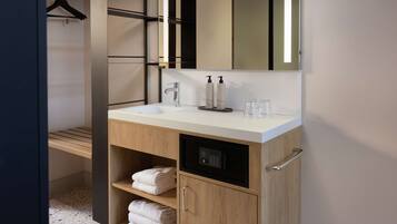 Ein modernes Badezimmer mit einem weißen Waschbecken, Holzschränken und einer Duschkabine.