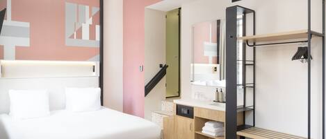 A modern bedroom with a bed, a vanity with a mirror, a built-in wardrobe, and a staircase.