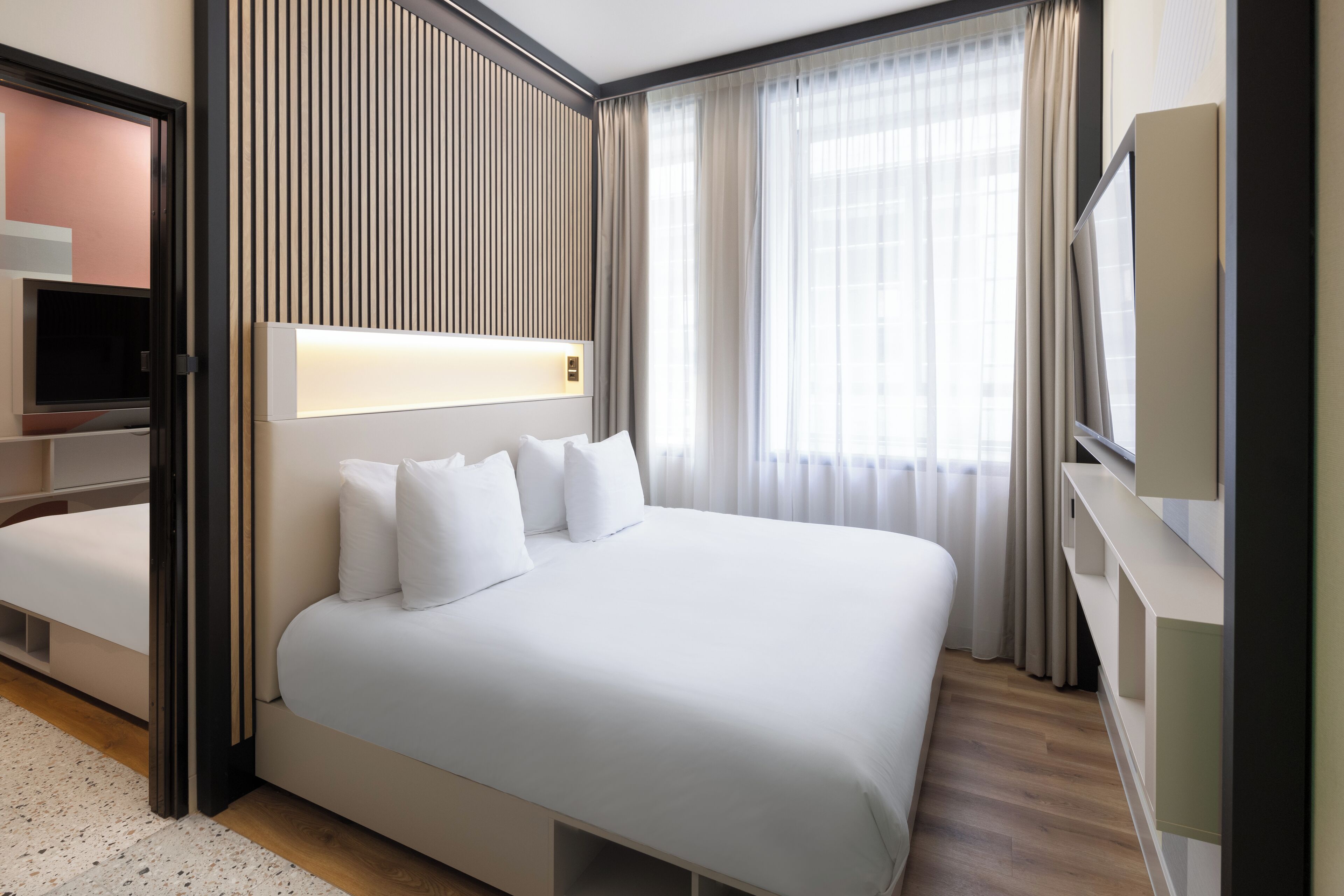 Een moderne hotelkamer met een groot bed, een televisie en een inbouwkast.