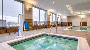 Ein Wellnessbereich mit Whirlpool, Liegestühlen und Blick auf die Stadt.