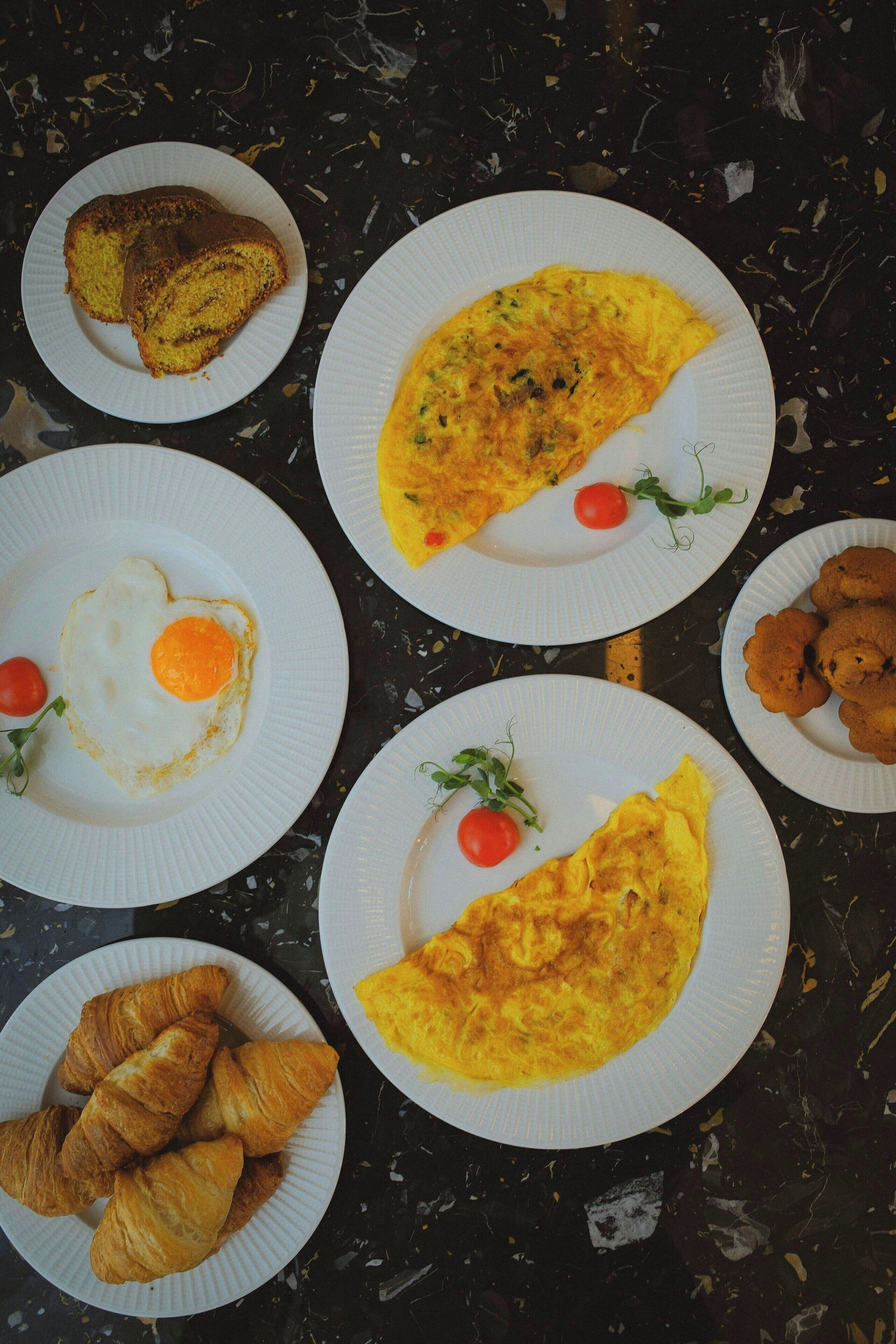 A table with various breakfast items including eggs, croissants, and a slice of toast.