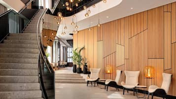 Un hall d’hôtel moderne avec un escalier à volutes, un espace salon et un éclairage décoratif.