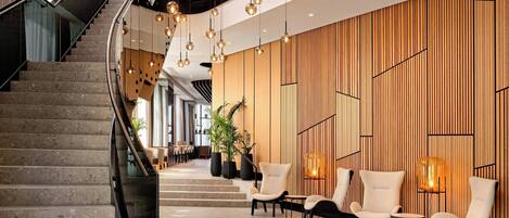 A modern hotel lobby with a curved staircase, seating area, and decorative lighting.