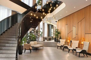 A modern lobby with a curved staircase, comfortable seating, and a wooden wall design.