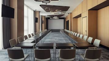 Una sala de conferències amb taules llargues i cadires, una pantalla gran i lluminàries modernes.