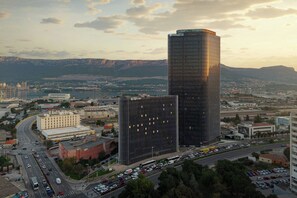 A high-rise building with a modern glass facade, surrounded by a busy urban area with roads and other buildings.