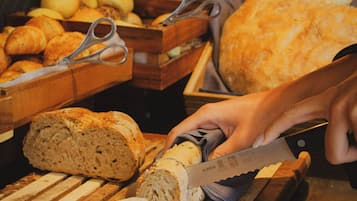 Una tabla de madera con pan rebanado, un cuchillo y un par de tijeras sobre una mesa.