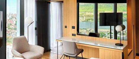 Une chambre d’hôtel moderne avec un grand lit, un bureau avec une chaise, une petite table et un téléviseur.