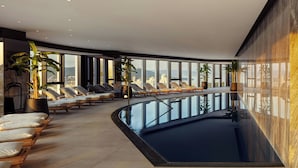 A modern indoor pool area with lounge chairs and potted plants, large windows offering a city view. - AC Hotel by Marriott Split (Split)