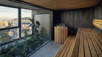 Habitación moderna con amplios ventanales que ofrecen vistas a la ciudad, un banco de madera y un pequeño arreglo de plantas.