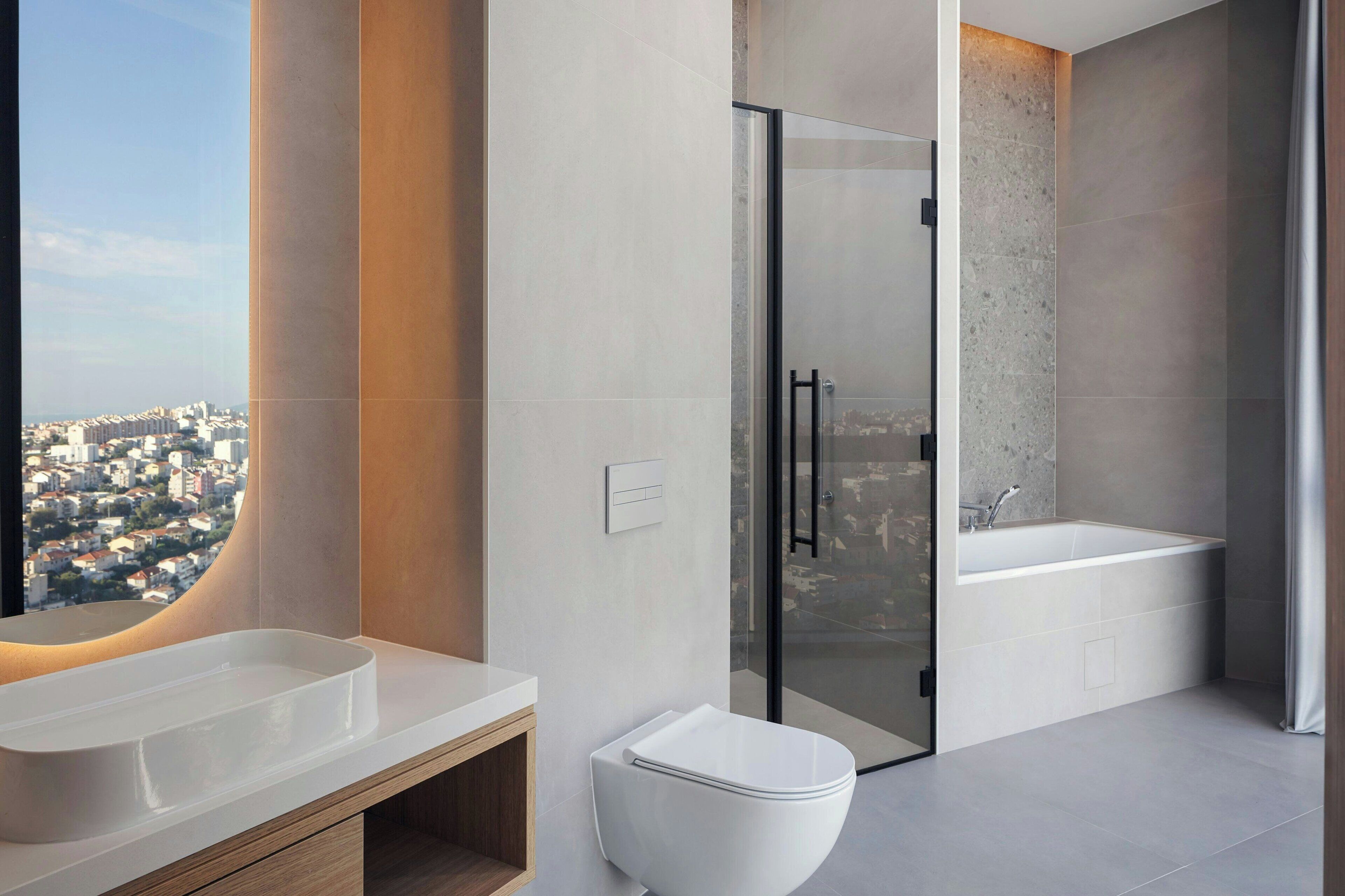 Een moderne badkamer met een ruime badkuip, een apart toilet en een douchecabine met glazen wanden.