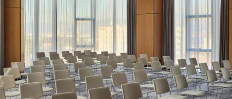 A conference room with rows of chairs, large windows, and a modern ceiling design.
