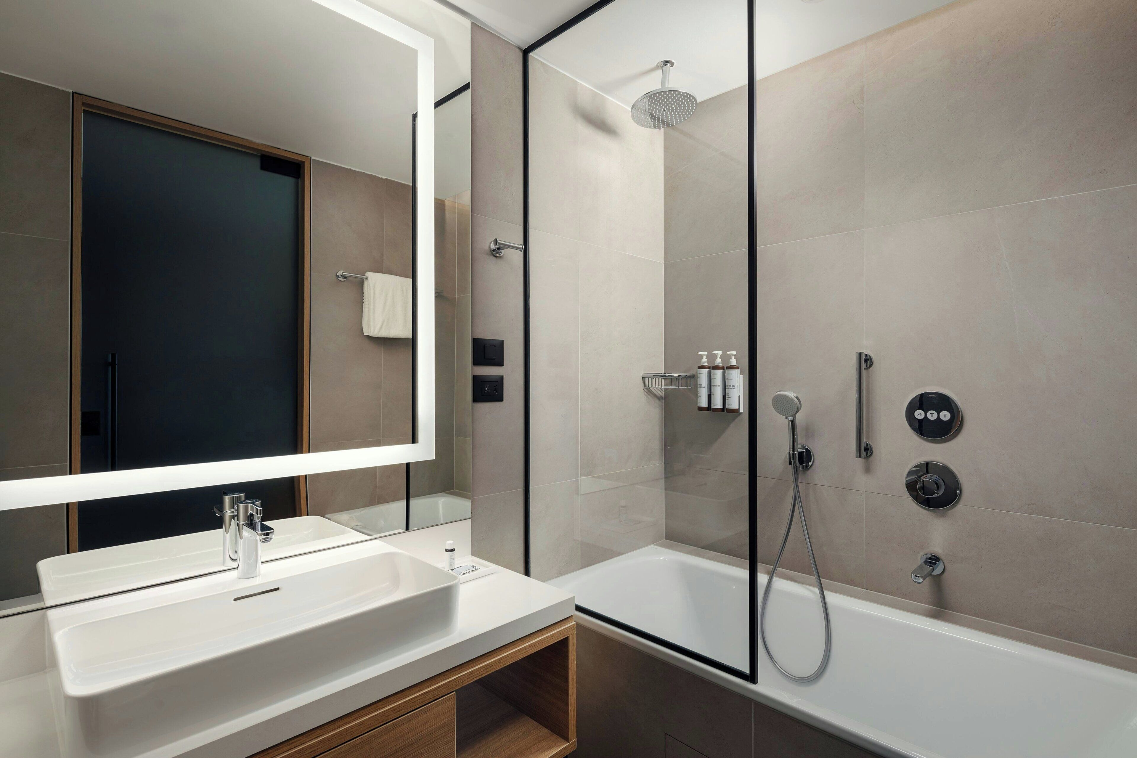 Un bany modern amb un mirall gran, un lavabo blanc, una dutxa i una banyera.