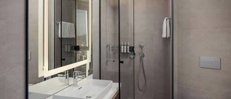 A modern bathroom with a glass-enclosed shower, a white sink, and a toilet.