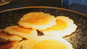 A cooking pan with several pancakes cooking on a stovetop.