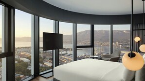 A bedroom with a large bed, a TV mounted on the wall, and a view of a cityscape through large windows. - AC Hotel by Marriott Split (Split)